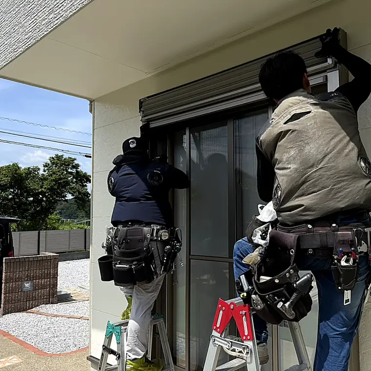 脚立に上がり窓シャッターを取り付けるリオールのスタッフ